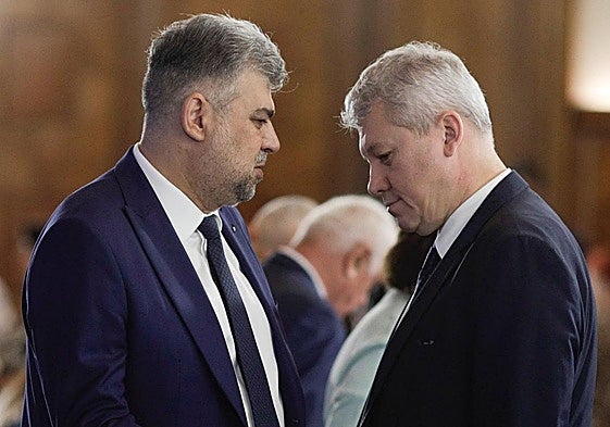 El hasta ahora primer ministro de Rumanía, Marcel Ciolacu (izquierda), conversa con su sucesor, Catalin Predoiu, que asume el cargo de forma interina.