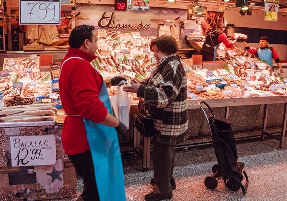 Una mujer recoge su compra en la pescadería.