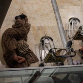 Dos personas sin hogar duermen junto a sus pertenencias en la T4 de Barajas.