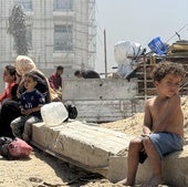 Varios niños sentados en los cascotes de las ruinas de Gaza.