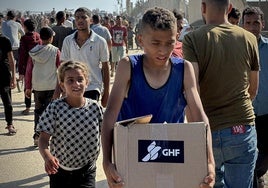 Un joven gazatí carga una caja con alimentos tras haber sido invadido el martes el centro de reparto de la organziación GHF.