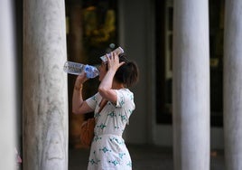 Una mujer bebe agua en Sevila.