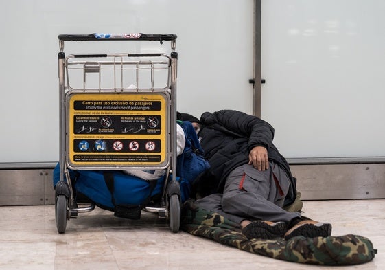 Un sinhogar duerme en el suelo de la terminar aérea madrileña de Barajas.