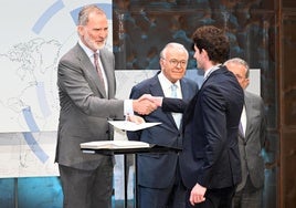 El Rey entrega su diploma a uno de los seleccionados ante la mirada atenta de Isidro Fainé, presidente de la Fundación 'La Caixa'.