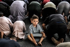Un niño mira a la cámara mientras decenas de civiles rezan con motivo del Eid al-Adha en Gaza City.