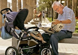 Un ciudadano lee un diario regional mientras se ocupa de su nieto en un parque andaluz.