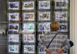 Una mujer mira anuncios en una inmobiliaria.