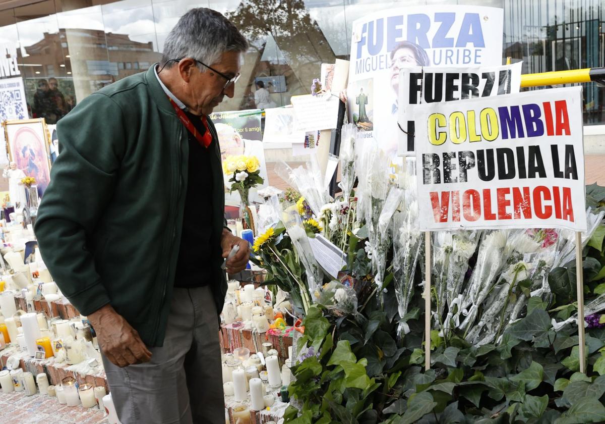 Un hombre observa un altar por Uribe Turbay frente a la Fundación Santa Fe de Bogotá.