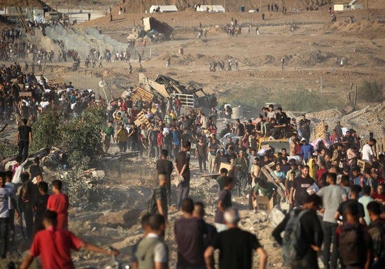 Decenas de gazatíes se congregan en torno a un punto de reparto de ayuda humanitaria.