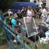 Residentes de Dnipropetrovsk aguardan con sus pertenencias junto a un edificio atacado por Rusia.