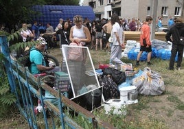 Residentes de Dnipropetrovsk aguardan con sus pertenencias junto a un edificio atacado por Rusia.