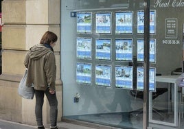 Una mujer mira anuncios de una inmobiliaria.