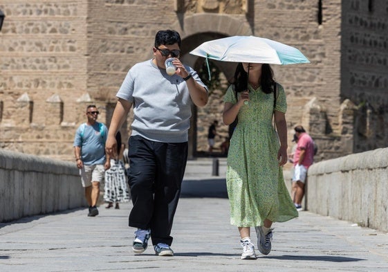 Turistas se protegen del sol durante la ola de calor en Toledo.