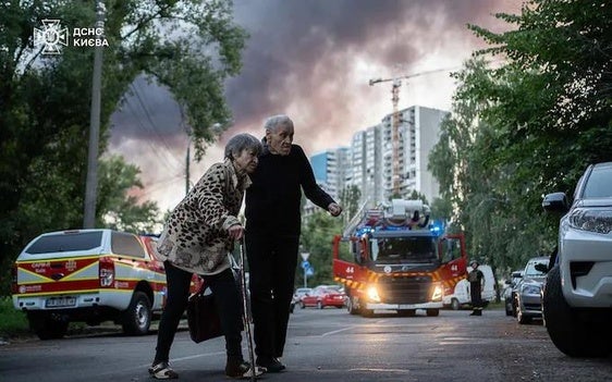 Una pareja mayor se apresura a llegar a su casa ante la alarma por contaminación tóxica en Kiev tras los bombardeos.