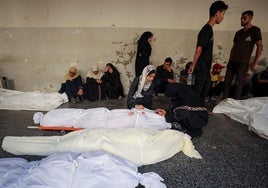 Palestinos lloran junto a varios cadáveres tras un ataque israelí contra una escuela de la UNRWA en Gaza donde se refugiaban desplazados.