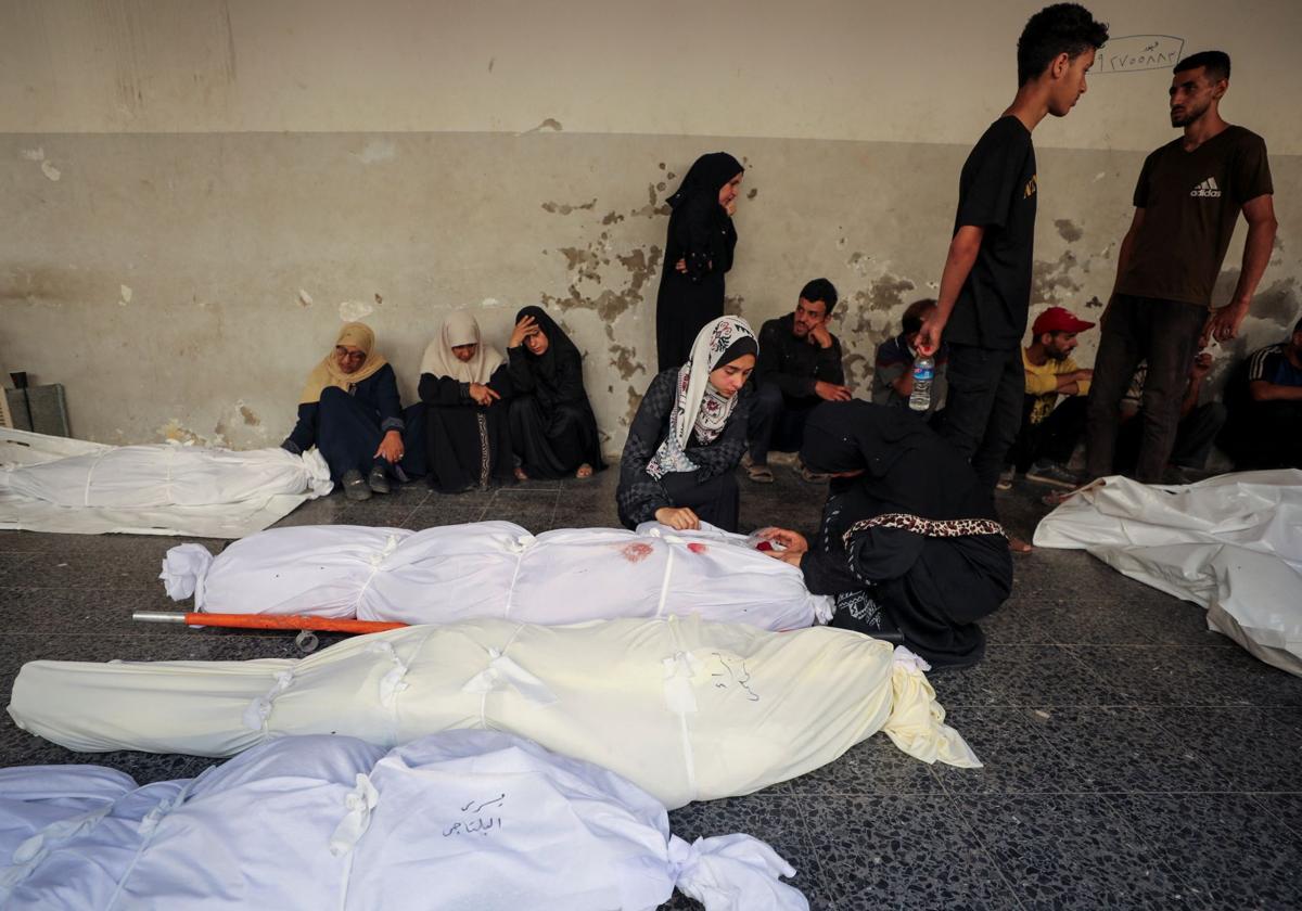 Palestinos lloran junto a varios cadáveres tras un ataque israelí contra una escuela de la UNRWA en Gaza donde se refugiaban desplazados.