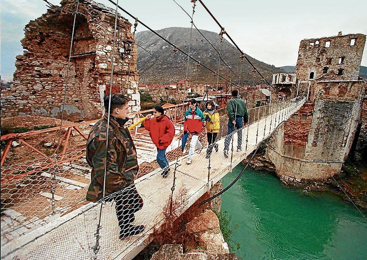 Imagen secundaria 1 - Una mujer corre mientras un soldado la protege de un francotirador, un puente colgante reemplaza al antiguo Mostar, en Bosnia en 1995, y Radovan Karadzic con uniforme militar.