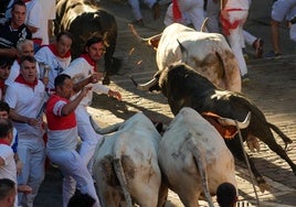 Los mozos son perseguidos por toros de la ganadería Victoriano del Río Cortés durante el cuarto encierro de los Sanfermines, este jueves, en Pamplona
