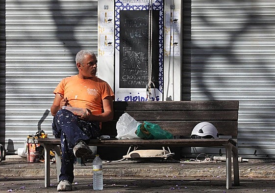 Un trabajador descansa en un banco.