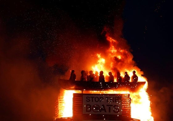 Arde una hoguera con muñecos de migrantes en una patera, en Moygashel.