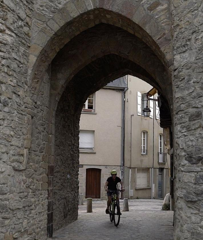 Imagen secundaria 2 - Arriba, casas de entramado de madera, típicas del casco medieval. A la izquierda, una mujer observa varias obras en el Museo de Arte Naif y Artes Singulares ubicado en el castillo de Laval. A la derecha, la puerta Beucheresse, en cuya torre nació el pintor naíf Henri Rousseau.