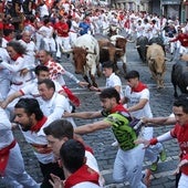 Los toros de la ganadería Jandilla persiguen a los mozos a su paso por la curva de Mercaderes durante el quinto encierro de los Sanfermines este viernes en Pamplona.