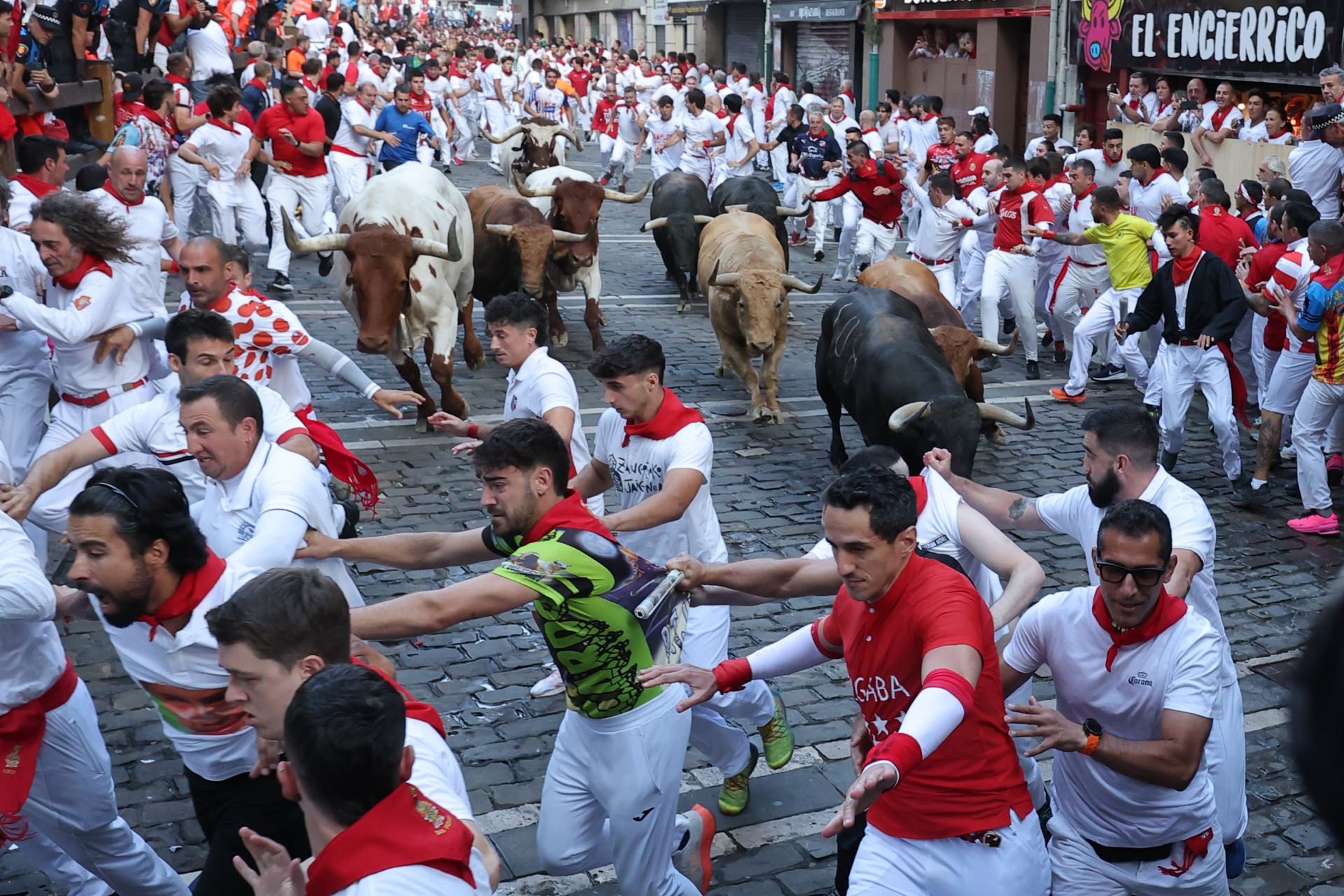 Los toros de la ganadería Jandilla persiguen a los mozos a su paso por la curva de Mercaderes durante el quinto encierro de los Sanfermines este viernes en Pamplona