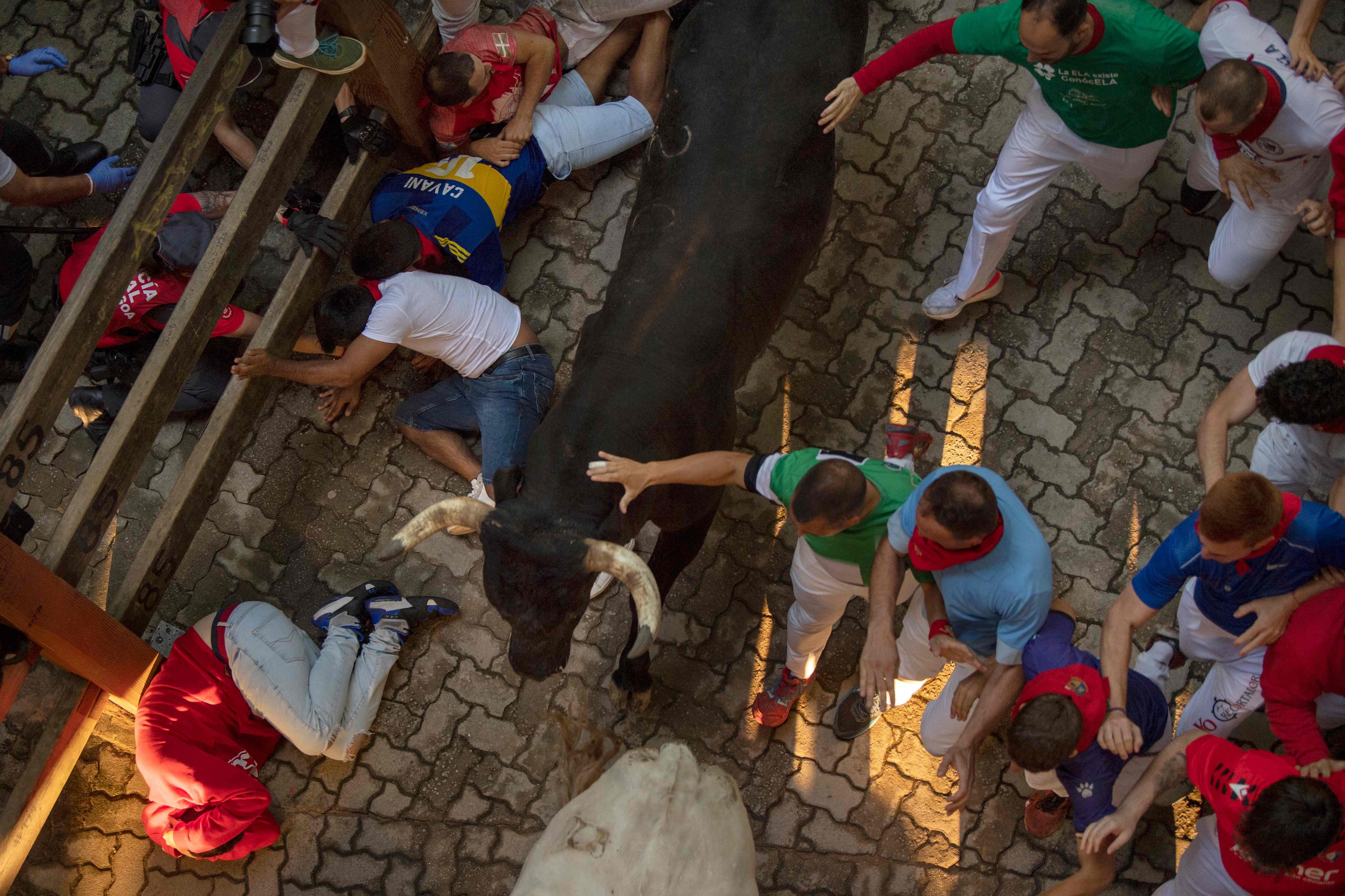Varios mozos en el suelo de la entrada a la plaza de toros de Pamplona.