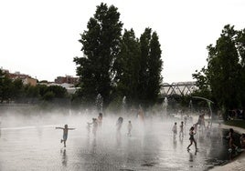 Un grupo de niños juega y se refresca en un parque de Madrid.