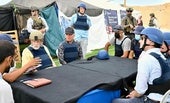 Los emisarios estadounidenses Steve Witkoff y Mike Huckabee escuchan las explicaciones en un centro de distribución de alimentos en Gaza.