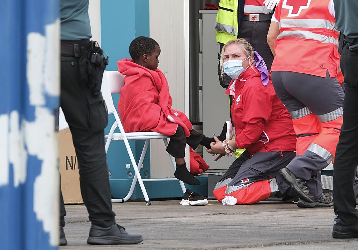 Una trabajadora de Cruz Roja atiende a un menor llegado en cayuco a Tenerife.