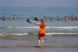 Una socorrista hace señales a un grupo de bañistas en la playa de Arriatera. .