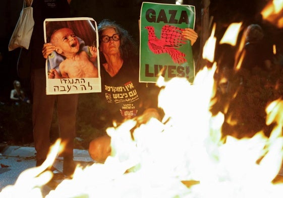 Familiares y simpatizantes de los rehenes israelíes retenidos por Hamás en Gaza portando antorchas, pancartas y fotos de los rehenes protestan frente a la oficina del primer ministro israelí durante una sesión del gabinete de seguridad.