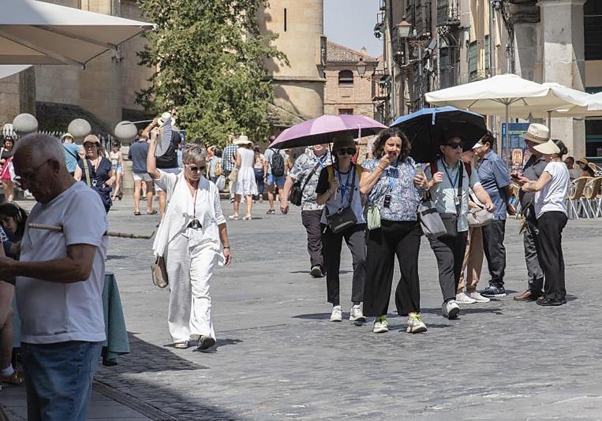 varias personas se protegen del sol con apraguas.