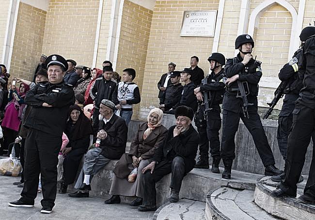 Policías chinos armados con fusiles automáticos frente a una mezquita de Xinjiang.