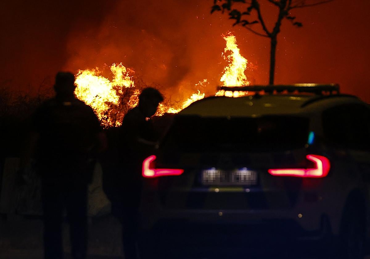 Una pareja de la Guardia Civil vigila la zona cercana al lugar del incendio en Tres Cantos (Madrid).