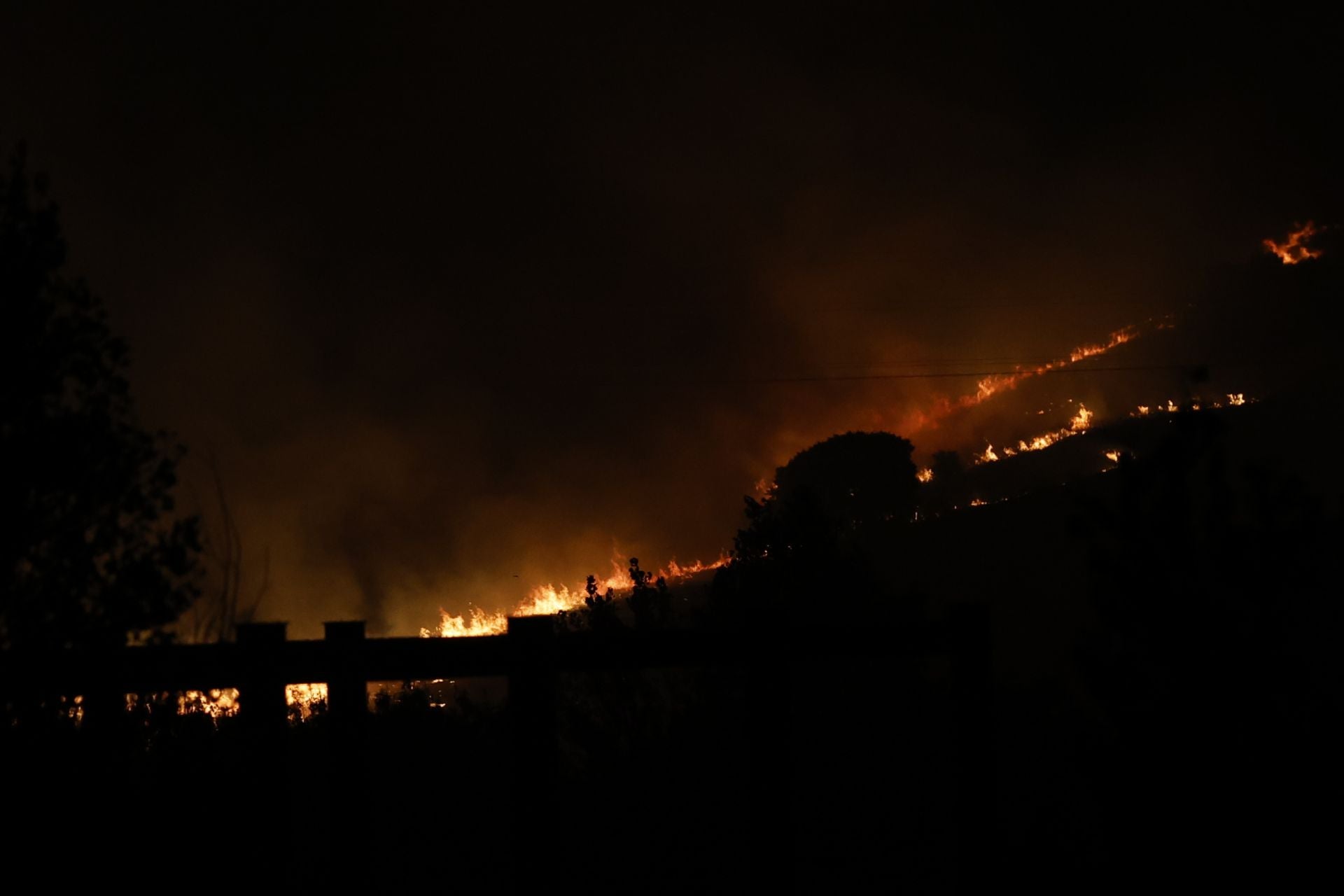 Imagen secundaria 1 - En la imagen superior, acceso a una de las urbanizaciones que ha tenido que ser desalojada por su cercanía al incendio desatado este lunes; debajo, avance de las llamas en una zona de vegetación y pastos; por último, una dotación de Bomberos de Madrid en la carretera M-607 de Colmenar Viejo camino de ayudar en la extinción del fuego en Tres Cantos.