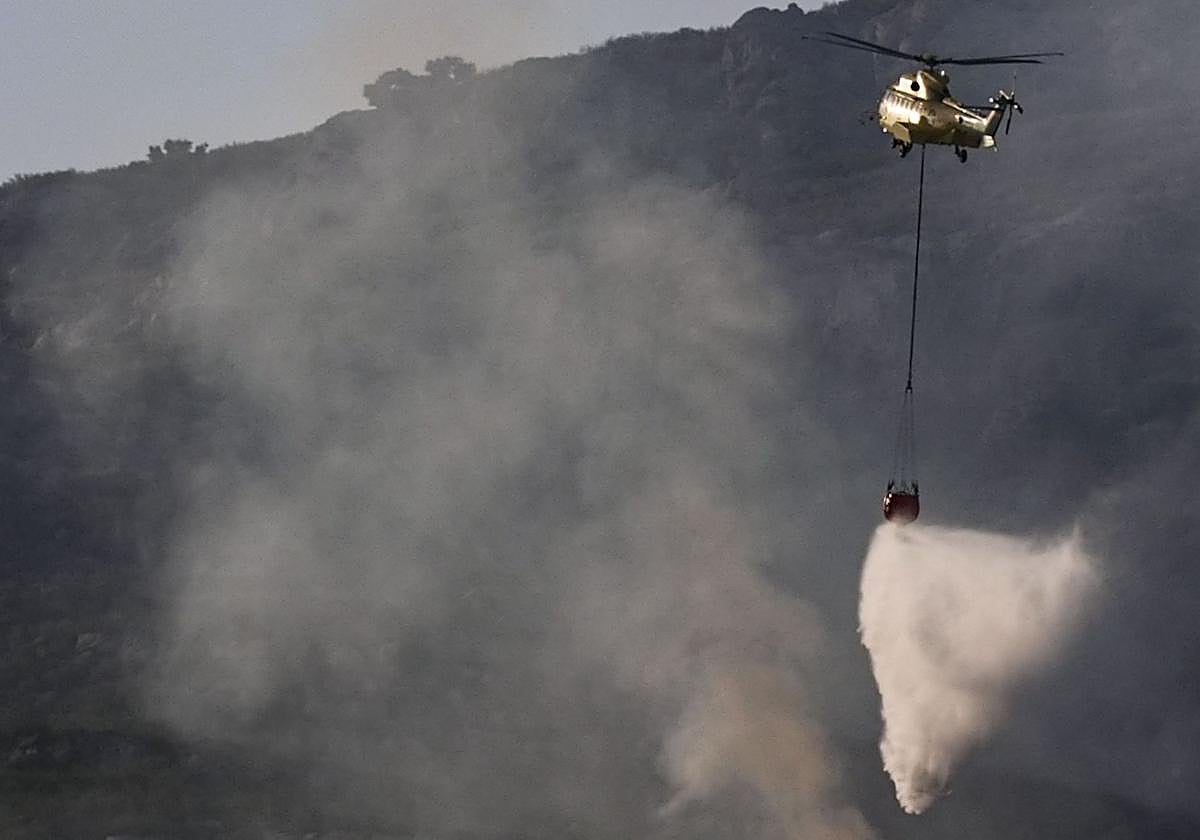 Un helicóptero trabaja en las labores de extinción del incendio que afecta a la Sierra de la Plata, en Tarifa (Cádiz)