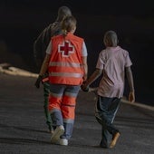 Una trabajadora de Cruz da la mano a un menor llegado en un cayuco a El Hierro.