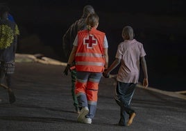 Una trabajadora de Cruz da la mano a un menor llegado en un cayuco a El Hierro.