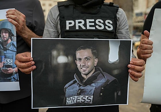 Un periodista sirio sostiene una fotografía de un periodista palestino fallecido.