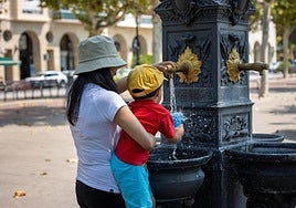 Una mujer y un niño llenan una botella para beber agua en Logroño