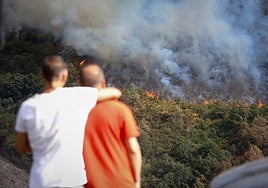 Varias personas observan el incendio, en la sierra de O Courel.