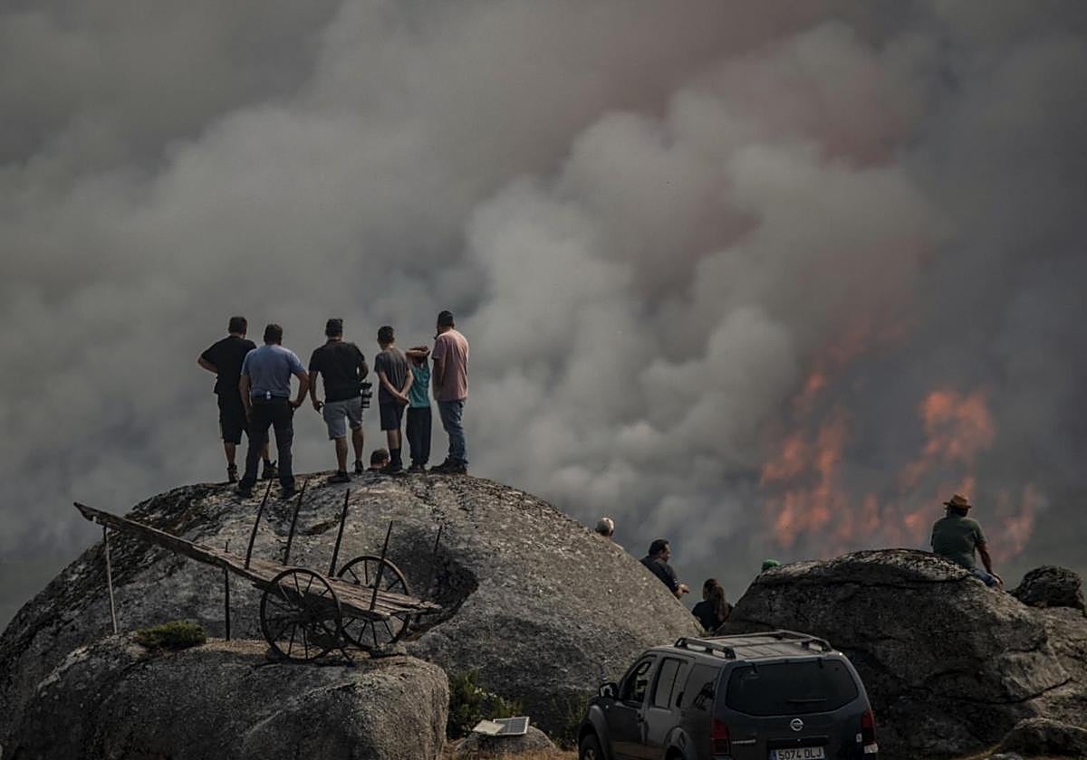 Varias personas observan el incendio forestal declarado ayer en Avión (Ourense), este lunes