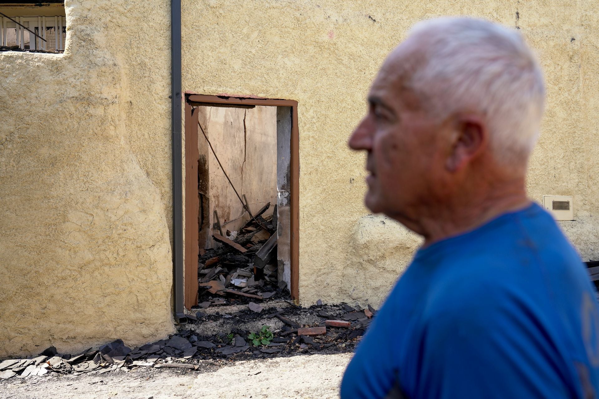 Ramiro Folla enfrente de unas de las casas quemadas del pueblo.