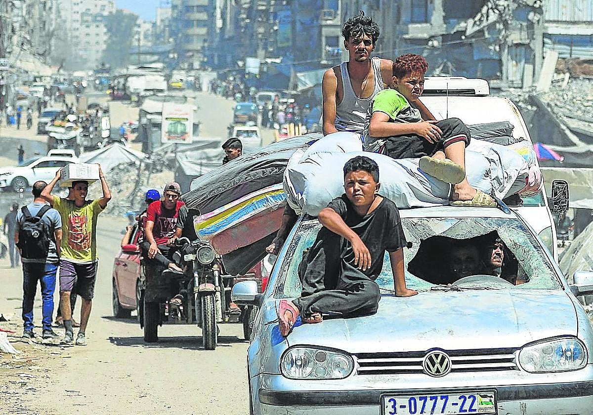 Palestinos huyen de un lugar a otro de Ciudad de Gaza cargados con sus enseres.