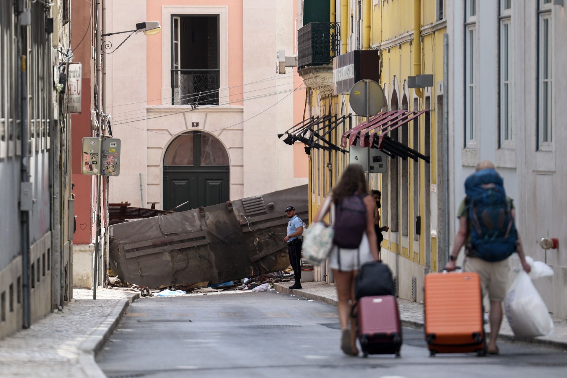 Un policía permanece junto a los restos del ascensor Gloria (funicular) de Lisboa, un popular medio de transporte para turistas, que descarriló este miércoles en Lisboa.