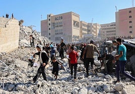 Decenas de palestinos caminan entre los escombros de un edificio de Ciudad de Gaza.