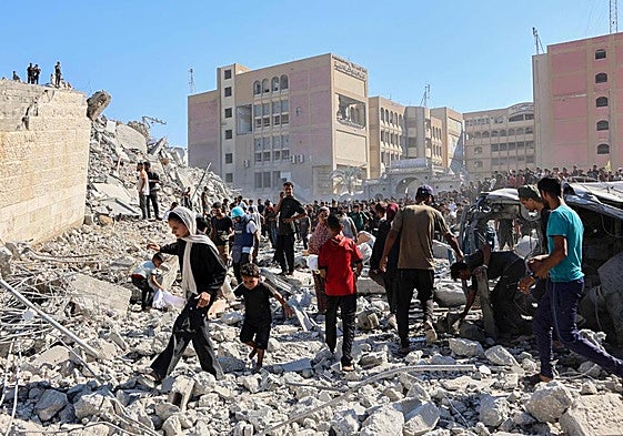 Decenas de palestinos caminan entre los escombros de un edificio de Ciudad de Gaza.