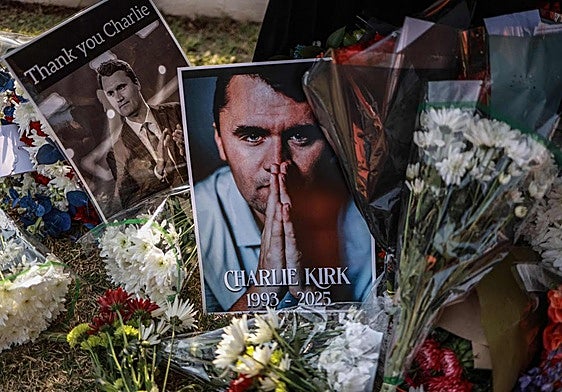 Un hombre sostiene un retrato de Charlie Kirk durante una vigilia.